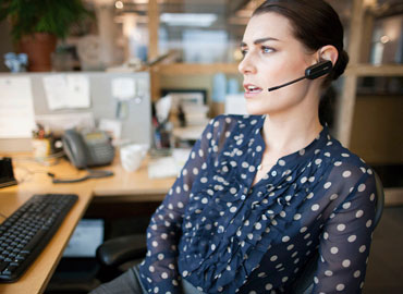 Una trabajadora llamando con un auricular de Platronics. 