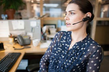 Una empleada llamando con un auricular de Plantronics. Una empleada llamando con un auricular de Plantronics.