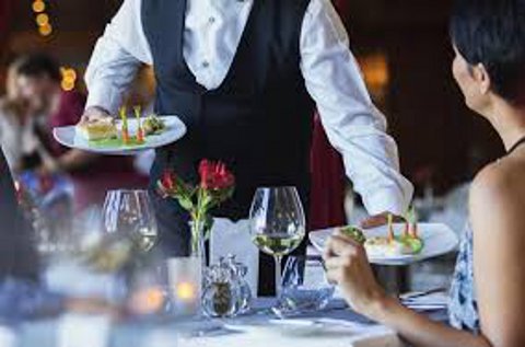 Un camarero sirve a una clienta en un restaurante. Un camarero sirve a una clienta en un restaurante.