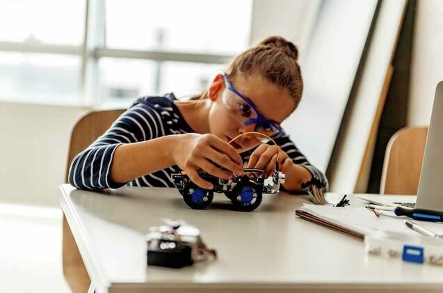 Una niña manipula un pequeño robot. Una niña manipula un pequeño robot.
